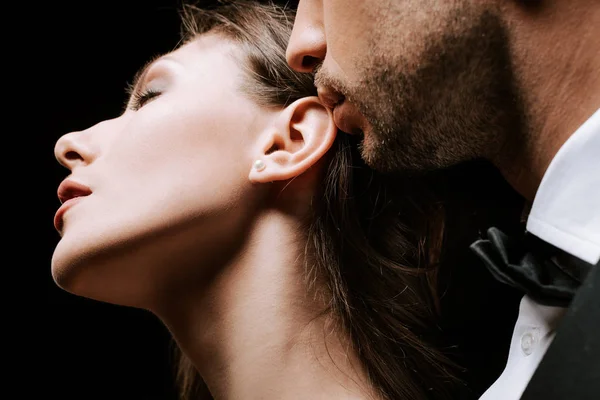Recortado vista de hombre cerca sensual chica con los ojos cerrados aislado en negro - foto de stock