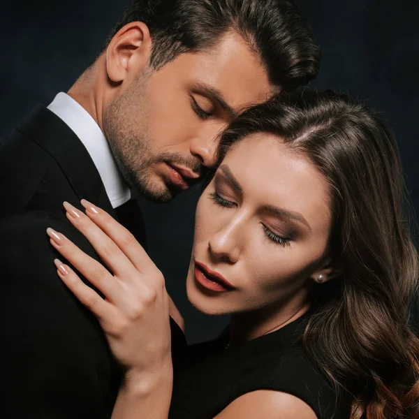 Junge und attraktive Frau umarmt gutaussehenden Mann isoliert auf schwarz — Stockfoto