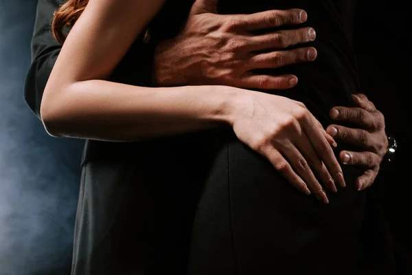 Corte vista de homem abraçando mulher no preto com fumaça — Fotografia de Stock