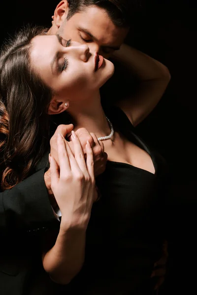 Man embracing young woman in dress on black — Stock Photo