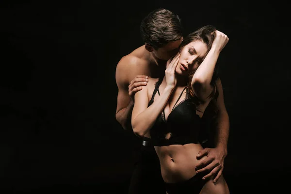 Seducente uomo e appassionato donna abbracciare isolato su nero — Foto stock