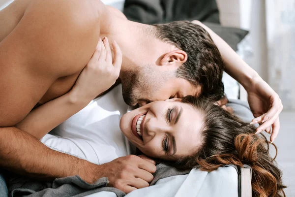 Homem apaixonado beijando menina feliz deitado na cama — Fotografia de Stock