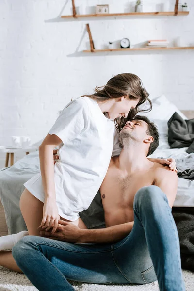 Chica atractiva mirando feliz novio muscular en el dormitorio - foto de stock