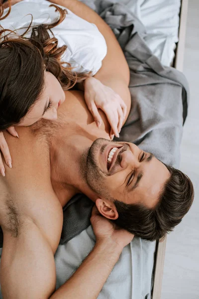 Top view of happy young woman lying on bed with muscular boyfriend — Stock Photo