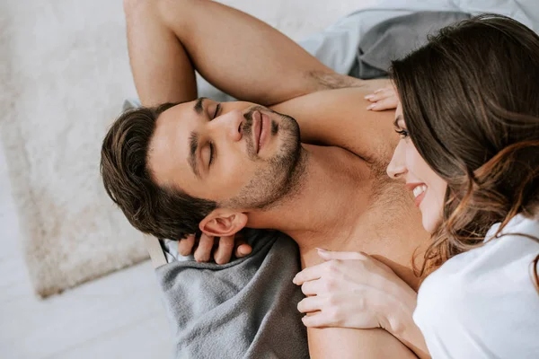 Vista dall'alto della giovane donna sorridente sdraiata sul letto con il fidanzato muscolare — Foto stock