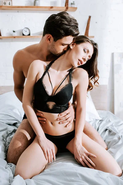 Без рубашки мужчина целует соблазнительную девушку в спальне — стоковое фото
