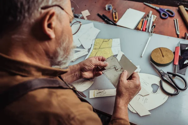 Selective focus of cobbler holding templates for shoemaking in workshop — Stock Photo
