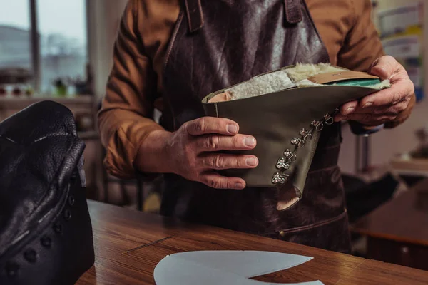 Vista recortada de zapatero sosteniendo detalle de cuero de zapato inacabado en taller — Stock Photo