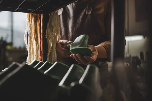 Vue partielle du cordonnier tenant la chaussure dernière en atelier — Photo de stock