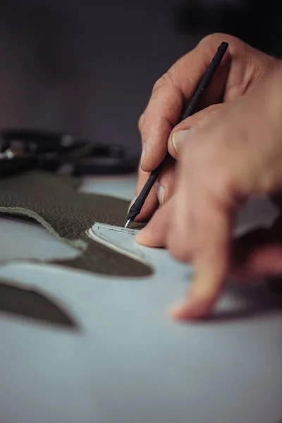 Partial view of shoemaker marking leather with special pen near template — Stock Photo