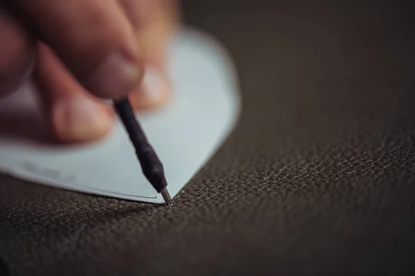 Close up view of leather marking pen in hands of shoemaker — Stock Photo