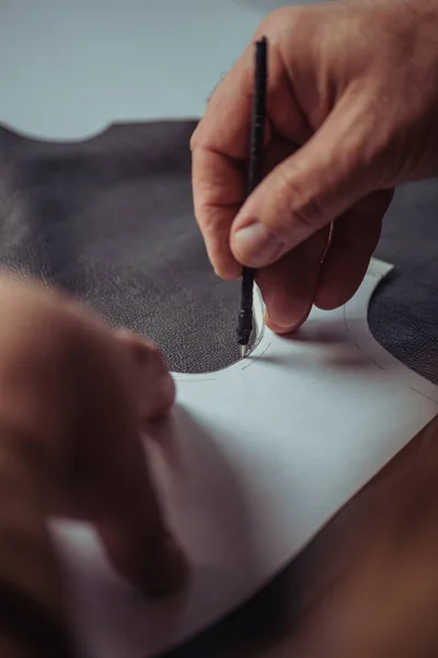 Cropped view of shoemaker marking leather with special pen near template — Stock Photo