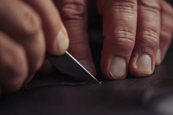 Ausgeschnittene Ansicht eines Schusters, der echtes Leder mit einem Messer schneidet — Stockfoto