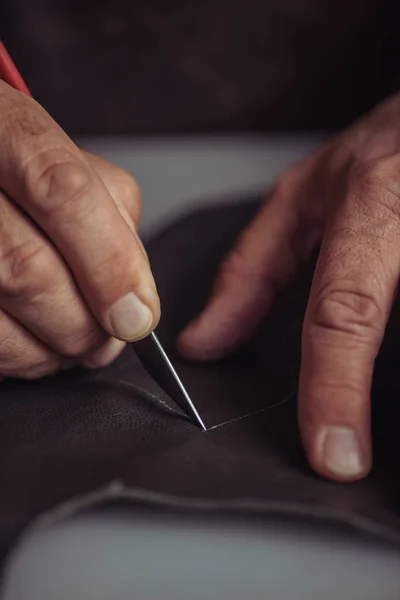 Cropped view of cobbler cutting genuine leather with knife — Stock Photo