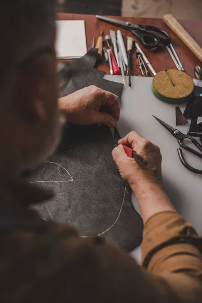 Vista recortada de zapatero de corte de cuero genuino con cuchillo en el taller - foto de stock