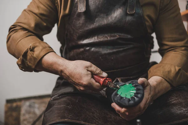 Ausgeschnittene Ansicht eines Schusters, der Nägel mit einer Zange aus dem Schuh entfernt — Stockfoto