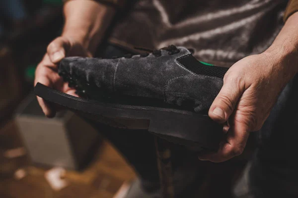 Cropped view of cobbler holding suede shoe with unfixed sole in workshop — Stock Photo