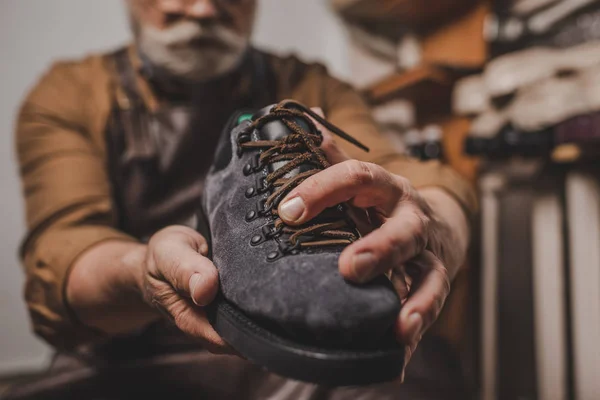 Messa a fuoco selettiva del calzolaio che tiene scarpe scamosciate in officina — Foto stock