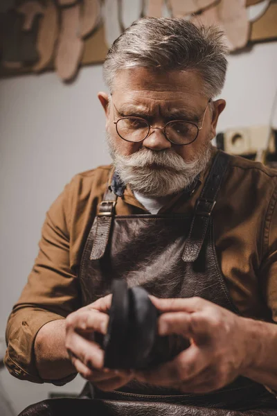 Senior, bearded cobbler repairing shoe in workshop — Stock Photo