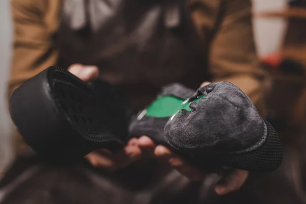 Selective focus of shoemaker holding shoe and sole in workshop — Stock Photo