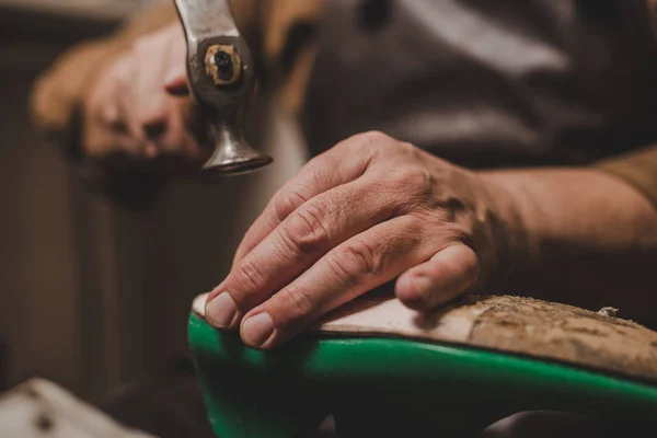 Ausgeschnittene Ansicht eines Schusters, der beim Reparieren von Schuhen in der Werkstatt einen Brummer hält — Stockfoto