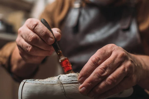 Cropped view of shoemaker applying glue on shoe with brush — Stock Photo