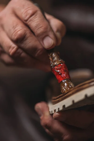 Cropped view of cobbler applying glue on sole with brush — Stock Photo