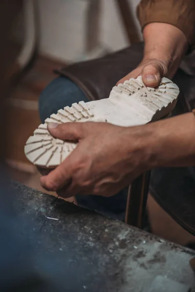 Partial view of shoemaker fixing sole to boot in workshop — Stock Photo