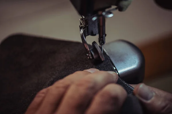 Частичный вид сапожника, пришивающего натуральную кожу к швейной машинке — стоковое фото