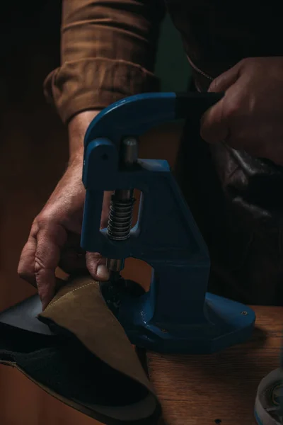 Cropped view of shoemaker making holes in leather with puncher — Stock Photo