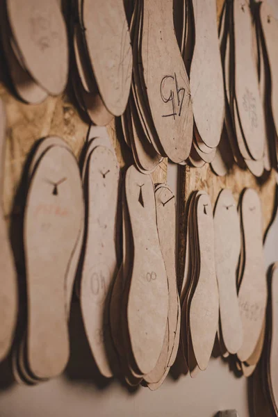 Foco seletivo de palmilhas de calçado de diferentes tamanhos pendurados na parede na oficina — Fotografia de Stock