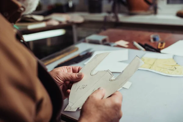 Cropped view of cobbler holding paper template in workshop — Stock Photo