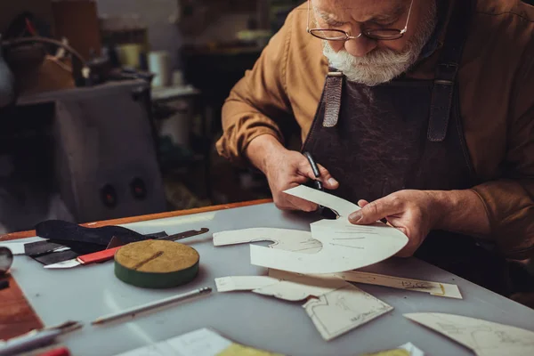 Senior, concentrato ciabattino modello di taglio in officina — Foto stock