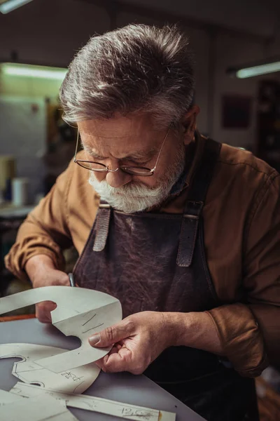 Attento, calzolaio anziano ritaglio modello in officina — Foto stock