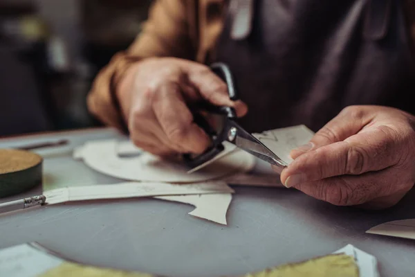 Cropped view of shoemaker cutting out template in workshop — Stock Photo