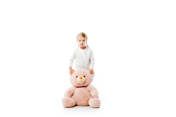 Adorable enfant debout avec ours en peluche rose, isolé sur blanc — Photo de stock