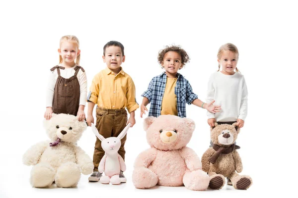 Happy multicultural kids standing with teddy bears and bunny toy — Stock Photo