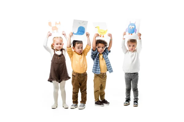 Niños multiculturales sosteniendo pinturas, aislados en blanco - foto de stock