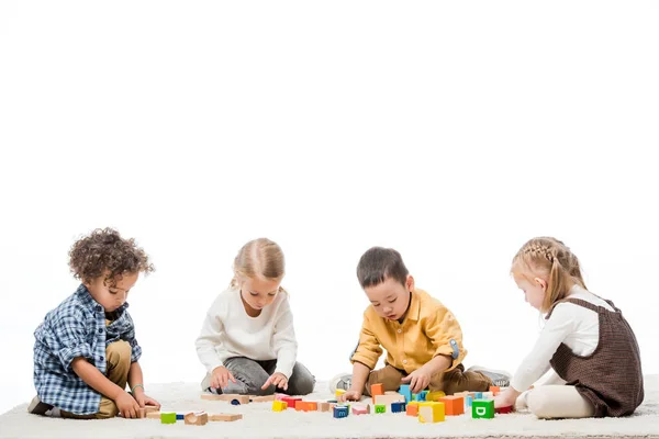 Multiethnische Kinder, die mit Holzklötzen auf Teppich spielen, isoliert auf Weiß — Stockfoto