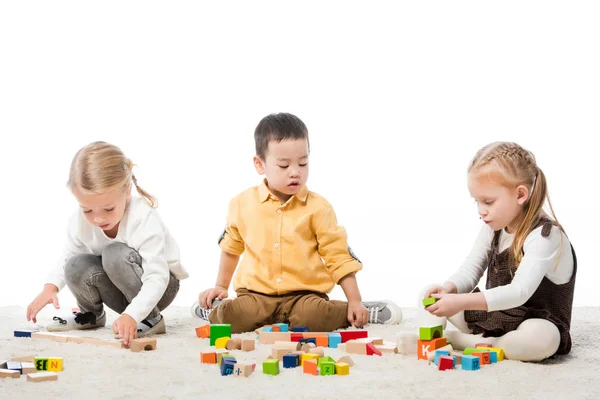 Multiethnische Kinder, die mit Holzklötzen auf Teppich spielen, isoliert auf Weiß — Stockfoto