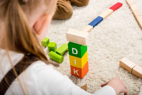 Vista recortada de los niños jugando con bloques de madera con palabra de niño en la alfombra - foto de stock