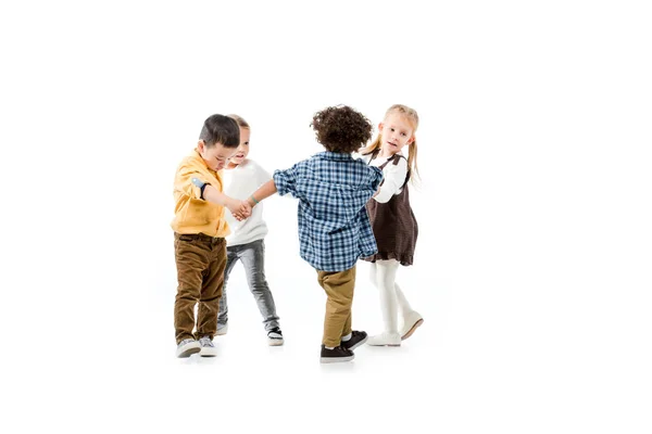 Adorabili bambini multiculturali che si tengono per mano e giocano isolati sul bianco — Foto stock