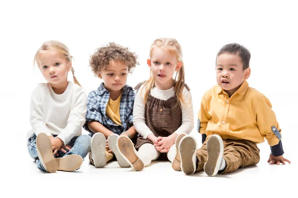 Entzückende multiethnische Kinder sitzen zusammen auf weißen Stühlen — Stockfoto