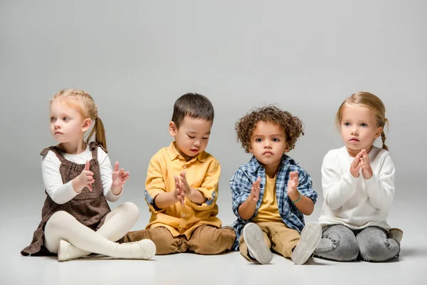 Adorable multicultural girls and boys playing on grey — Stock Photo