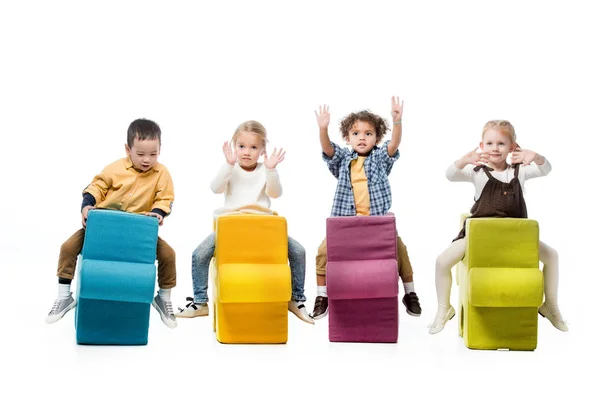 Multicultural kids playing and sitting on puzzles isolated on white — Stock Photo
