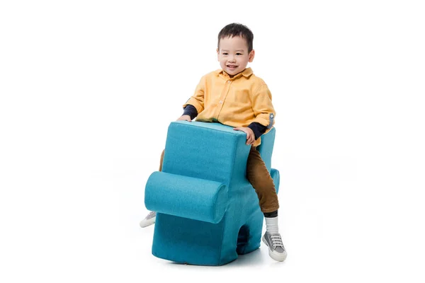 Smiling asian boy sitting on blue puzzle chair isolated on white — Stock Photo