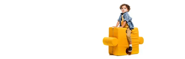 Plan panoramique de petit garçon afro-américain assis sur une chaise puzzle jaune, isolé sur blanc — Photo de stock