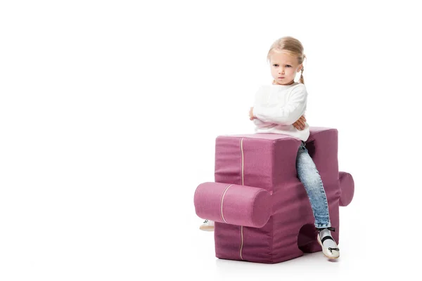 Offended kid sitting on purple puzzle chair, isolated on white — Stock Photo