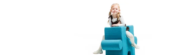 Tiro panorámico de niño feliz sentado en la silla del rompecabezas azul, aislado en blanco - foto de stock