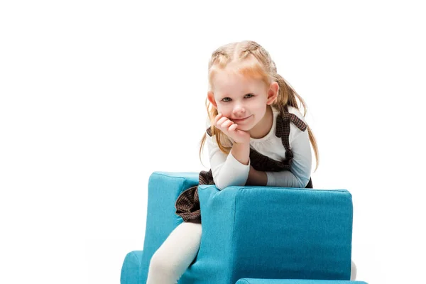 Мечтательный ребенок сидит на синем стуле головоломки, изолированный на белом — стоковое фото